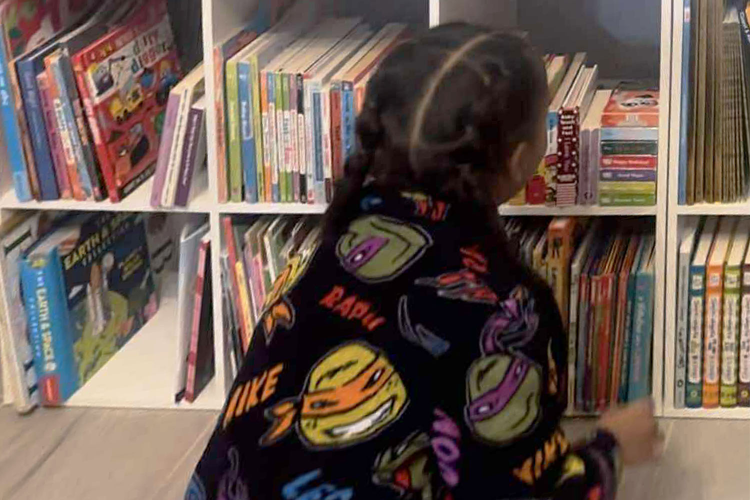 Josiah King Bethea looking at his mini library filled with children's books